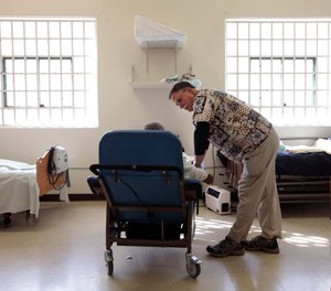 In this Sept. 12, 2012, file photo, Dr. David Mathis, visits with an inmate in the hospital unit at the California Medical Facility in Vacaville, Calif.
