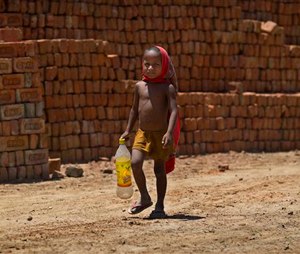 A young boy, son of a laborer, walks to a water pump to fill his bottle with drinking water on a hot summer day in Ghasera, on the outskirts of New Delhi, India, Wednesday, May 27, 2015. Delhi recorded a maximum temperature of 42 degrees Celsius on Wednesday. In southern India, hundreds of people have died since the middle of April as soaring summer temperatures scorch the country, officials said Tuesday. (AP Photo/Saurabh Das)