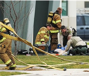 Rescue personnel from multiple agencies perform CPR on a patient at the site of a helicopter crash into a building. (AP Photo/Deseret News, Scott G Winterton)