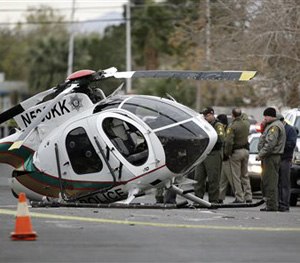 Las Vegas police officers stand by the wreckage of a Las Vegas police helicopter Wednesday, Dec. 31, 2014, in Las Vegas.