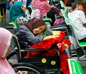 A patient takes a nap on her wheelchair as she waits with others at the registration desk at Dharmais Cancer Hospital in Jakarta, Indonesia. (AP Photo/Dita Alangkara)