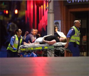 A injured hostage is wheeled to an ambulance after shots were fired during a cafe siege at Martin Place in the central business district of Sydney, Australia, Dec. 16, 2014. (Rob Griffith/AP Photo)