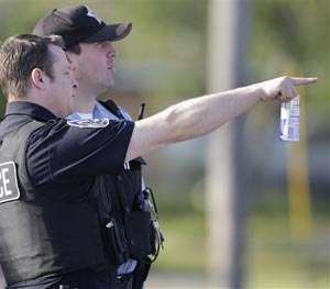 Police stage at an intersection as law enforcement officials continue to negotiate with at least one hostage-taker for the release of two children and two adults he is still holding inside a house in the southern Chicago suburb of Harvey, Wednesday, Aug. 20, 2014. The standoff began at 12:45 p.m. Tuesday when Harvey police responded to reports from a neighbor of a possible burglary at the home. Two officers were wounded in an initial exchange of gunfire. (AP Image)