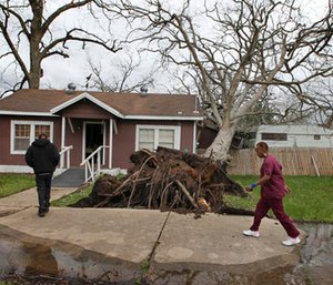 Cheryl Bradshaw, right, and her son Jerard walk past a toppled tree that separated her bathroom from her home Tuesday. (Steve Gonzales/Houston Chronicle via AP)