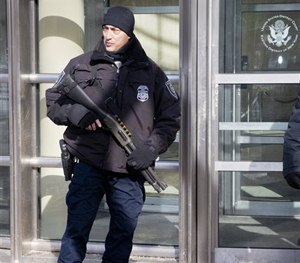 A Homeland Security officer shows his weapon as part of enhanced security, during the arraignment of two men on terrorism related charges, Feb. 25, 2015.