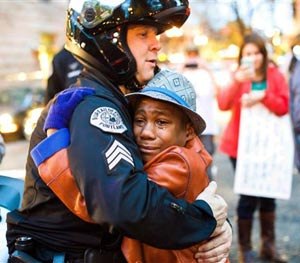In this Tuesday, Nov. 25, 2014 photo provided by Johnny Nguyen, Portland police Sgt. Bret Barnum, left, and Devonte Hart, 12, hug at a rally in Portland, Ore., where people had gathered in support of the protests in Ferguson, Mo.