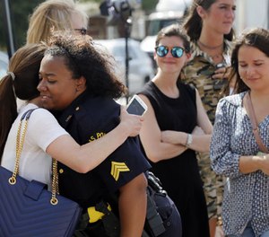 A well-wisher hugs Dallas police Sgt. Jamie Matthews, right, as they both visit a makeshift memorial in front of the departments headquarters, Monday, July 11, 2016, in Dallas. (AP Photo/Tony Gutierrez)