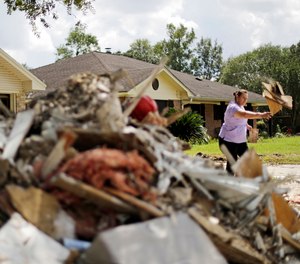 Maria Rocha places debris outside her home in a neighborhood that was flooded by Hurricane Harvey in Beaumont, Texas, Tuesday, Sept. 26, 2017.