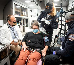 Dr. Jason Stopyra (far left) demonstrates using an i-STAT device with paramedics Callie Katers (second from right) and Bubba Killgo (far right), with Wake Forest Baptist employee Rebecca Overman standing in as a patient.