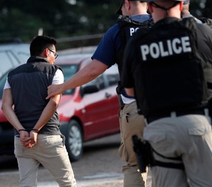 A man is taken into custody at a Koch Foods Inc. plant in Morton, Miss., on Wednesday, Aug. 7, 2019. (AP Photo/Rogelio V. Solis)