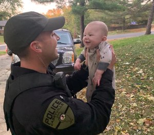 Officer Travis Hoguet holds up the infant he saved from choking on October 9, 2020. (Photo/Caseyville Police Department)