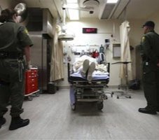Correctional officers stand watch over an inmate receiving treatment in the emergency room at California State Prison, Corcoran. (AP Photo/Rich Pedroncelli)