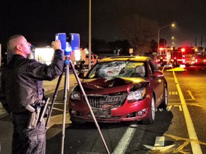 An officer uses a laser scanner to investigate the scene of an accident.