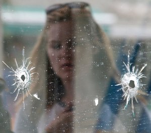 In this May 24, 2014 file photo, a woman looks at the bullet holes on the window of IV Deli Mark where a mass shooting took place near the University of California, Santa Barbara campus, in the Isla Vista beach community of Santa Barbara, Calif. (AP Photo/Jae C. Hong, file)