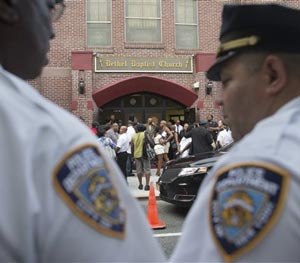In this July 23, 2014 file photo, a pair of New York City police officers stand at their post as mourners arrive for the funeral service of Eric Garner at Bethel Baptist Church in the Brooklyn borough of New York.
