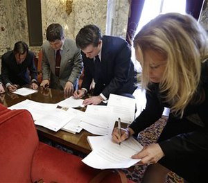In this May 8, 2013 file photo, attorney Lara Zarowsky, right, signs thank you notes to legislators with Innocence Project Northwest law student volunteers.