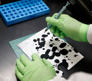 In this June 27, 2019 photo, document analysis technician Irvin Rivera collects samples of inkjet printer ink in the International Ink Library at the U.S. Secret Service headquarters building in Washington.