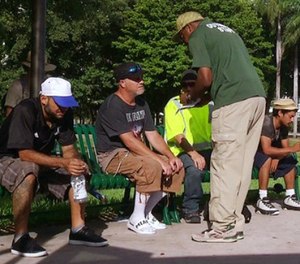 In this frame made from video on Fri., Sept. 8, 2017, an official in Miami speaks with homeless people about moving to shelters ahead of powerful Hurricane Irma. Officials detained at least five people to admit them into a psychiatric ward because they suspected a mental illness.