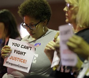 Alicia Street holds a sign as she sits in the audience during a meeting of the Ferguson City Council, Tuesday, March 15, 2016, in Ferguson, Mo.