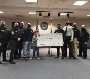 Mason Duffy and police officers pose with a check made out to the Little Ferry Police K-9 unit.