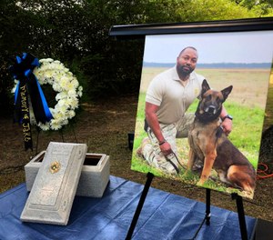 A Tuesday, July 30, 2019 photo shows Alabama K-9 Jake, who died after coming into contact with a narcotic during a prison contraband search, was honored Tuesday with a 21-gun salute and commendation from Gov. Kay Ivey at the Staton Kennel Complex in Elmore. Pictured in the portrait is Jakes handler Sgt. Quinton Jones. (AP Photo/Blake Paterson)