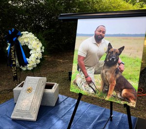 A Tuesday, July 30, 2019 photo shows Alabama K-9 Jake, who died after coming into contact with a narcotic during a prison contraband search, was honored Tuesday with a 21-gun salute and commendation from Gov. Kay Ivey at the Staton Kennel Complex in Elmore. Pictured in the portrait is Jakes handler Sgt. Quinton Jones.