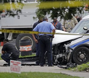 Investigators look over a New Orleans Police department vehicle in which one officer was shot and killed while transporting a prisoner in New Orleans, Saturday, June 20, 2015.