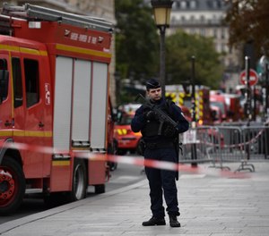 A policeman stands next to firefighter vehicles near Paris police headquarters on Oct. 3, 2019 after four officers were killed in a knife attack. The attacker was shot dead after killing four officers at police headquarters in the historical centre of Paris. (Martin Bureau/AFP/Getty Images/TNS)