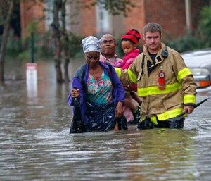 A member of the St. George Fire Department assists residents as they wade through floodwaters from heavy rains in the Chateau Wein Apartments in Baton Rouge, La., Friday, Aug. 12, 2016.
