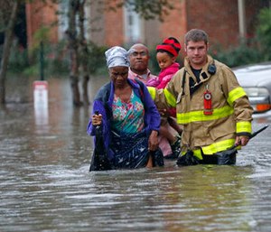 A member of the St. George Fire Department assists residents as they wade through floodwaters from heavy rains in the Chateau Wein Apartments in Baton Rouge, La., Friday, Aug. 12, 2016.