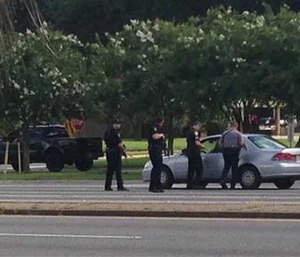 Authorities talk to the driver of a car near an area where several officers were shot while on duty less than a mile from police headquarters, Sunday, July 17, 2016. (AP Image)