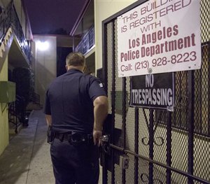 In this Tuesday, Oct. 27, 2015, photo, Los Angeles Police Department Sgt. Michael Gannon enters an apartment complex in South Los Angeles.