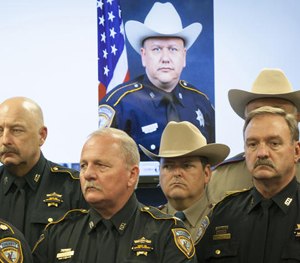 In this Saturday, Aug. 29, 2015 file photo, law enforcement officers attend a news conference in Houston on the shooting death of Harris County Sheriff's Deputy Darren Goforth, pictured in the background.