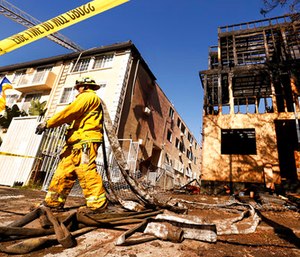 LA City Firefighter Jose Carreon hauling hoses on mop up at the scene. (Al Seib/Los Angeles Times via AP)