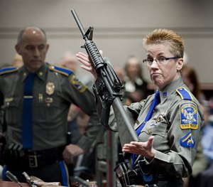 In this Jan. 28, 2013, file photo, firearms training unit Detective Barbara J. Mattson, holds up a Bushmaster AR-15 rifle, the same make and model of gun used by Adam Lanza in the shooting. (AP Image)
