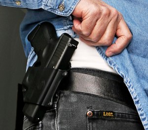 In this Feb. 27, 2013 file photo Hank Johnson displays his handgun, in Springboro, Ohio.