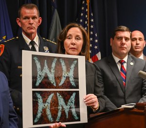 Suffolk County Police Commissioner Geraldine Hart shows a photograph with the initials on a belt, showing either an HM or WH, depending on the angle, during a press conference at police headquarters in Yaphank , N.Y. (Photo/AP)