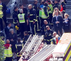 Britain's Prime Minister Theresa May, bottom left, speaks to firefighters and police officers after arriving at Grenfield Tower in London. (AP Photo/Frank Augstein)
