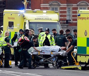 Emergency services transport an injured person to an ambulance, close to the Houses of Parliament in London, Wednesday, March 22, 2017.