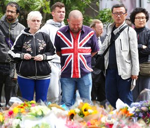 People look at flowers near London Bridge following Saturday's attack in London.