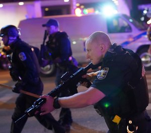 Police move after a Louisville Police officer was shot, Wednesday, Sept. 23, 2020, in Louisville, Ky. (AP Photo/John Minchillo)