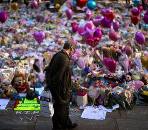 A man stands next to flowers for the victims of the bombing at St Ann's Square in central Manchester, England, Friday, May 26 2017.