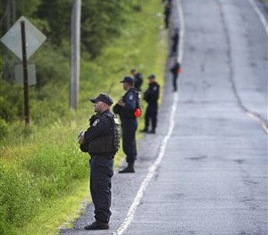 New York State corrections officers line the edge of the forest along County Route 41 in the town of Malone, N.Y. Friday evening, June 26, 2015.
