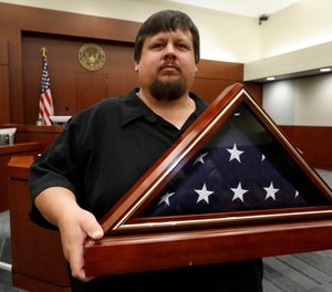 Gary Hulsey, a 40-year-old resident of Wylie, Texas, holds a folded flag that was presented to him at the United States Courthouse in Plano, Texas, Friday, July 26, 2019.
