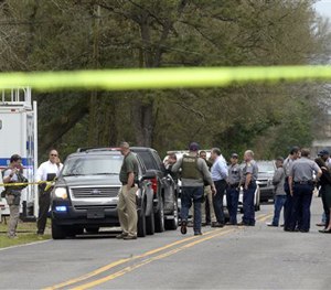 Law enforcement personnel gather in front of the Elm Grove Motel on Elm Grove Garden Road just north of Progress Road in Baton Rouge, La. (AP Image)