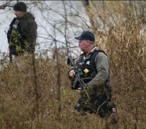 Anne Arundel police search the waters edge in the Stoney Beach community. The manhunt continues for a suspect in the shooting of two Anne Arundel police officers. (Photo/TNS)