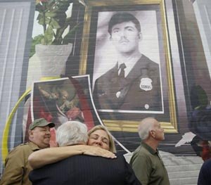 Maureen Faulkner, widow of slain Philadelphia police officer Daniel Faulkner, embraces Joe McGill who prosecuted Mumia Abu-Jamal for the murder of her husband, underneath a new mural of him, Monday, Nov. 24, 2014, in Philadelphia.