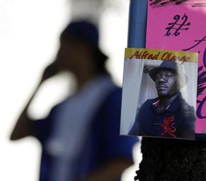 In this Sept. 28, 2016 file photo, a man stands behind a picture of Alfred Olango during a protest, in El Cajon, Calif.