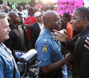 In this Aug. 16, 2014 file photo, Col. Ron Replogle, left, talks with Malik Shabazz, right, president of Black Lawyers for Justice and former chairman of the New Black Panther Party, in Ferguson, Mo.