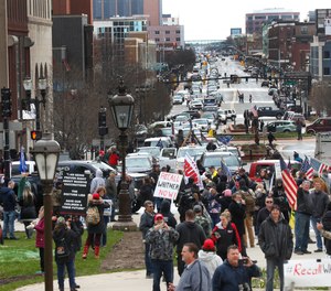 Flag-waving, honking protesters drove past the Michigan Capitol on Wednesday to show their displeasure with Gov. Gretchen Whitmer's orders to keep people at home and businesses locked during the COVID-19 outbreak.